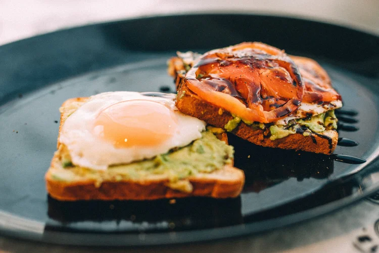Avocado toast topped with a fried egg and tomato