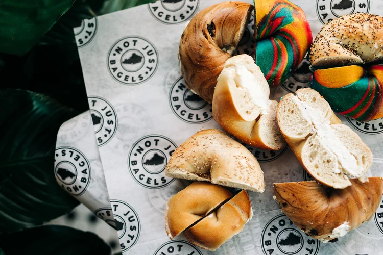 Colorful and plain bagels sliced open with cream cheese